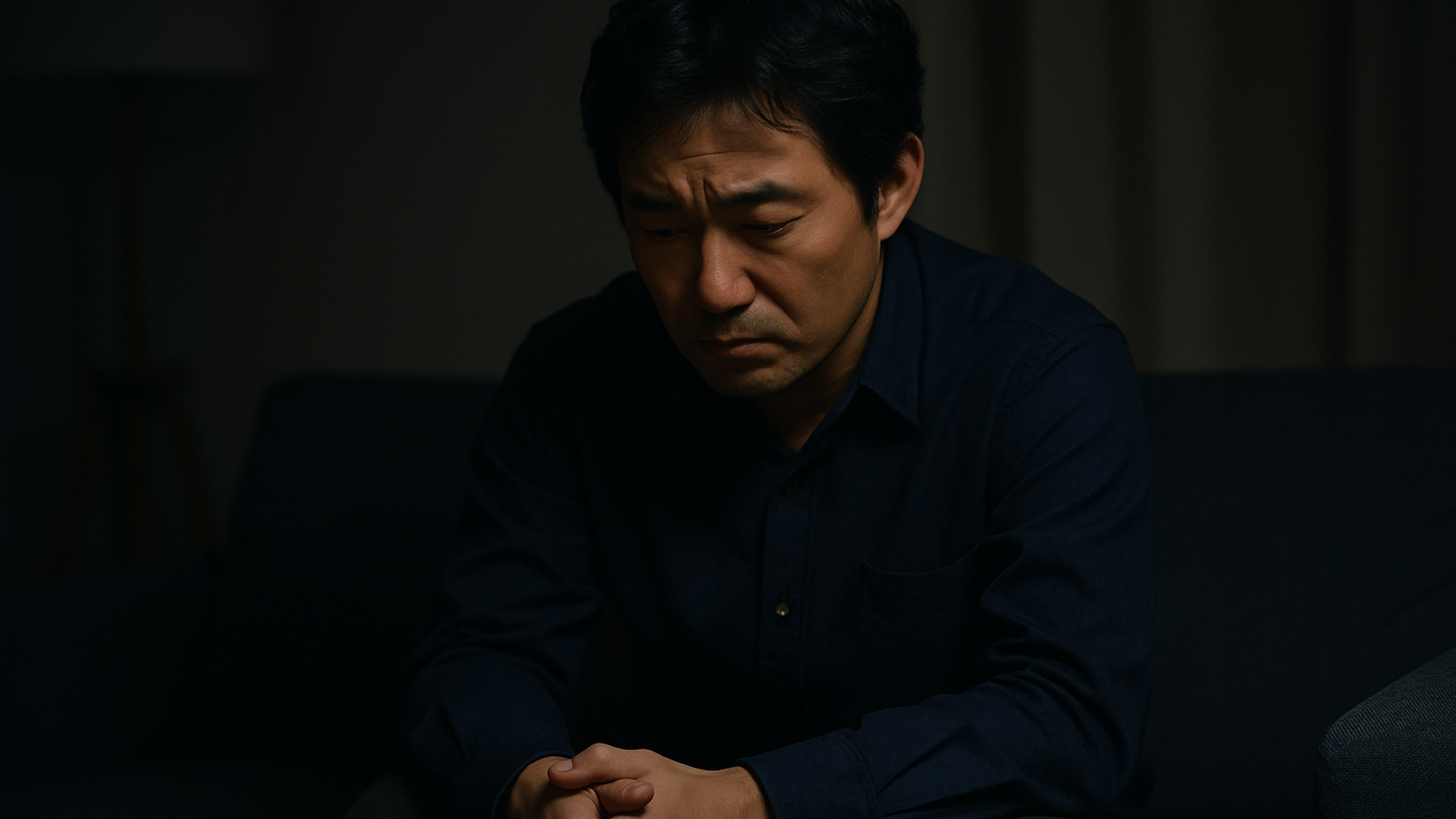 妻の浮気を疑い夜にソファで一人悩む男性のイメージ